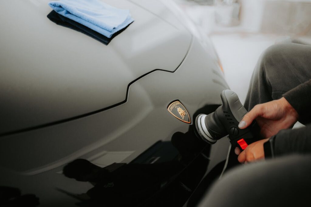 Detailed shot of a Lamborghini being polished, showcasing an automotive care process in a garage.